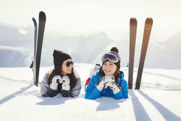 two young and active brunette sitting in the snowy mountains with ski